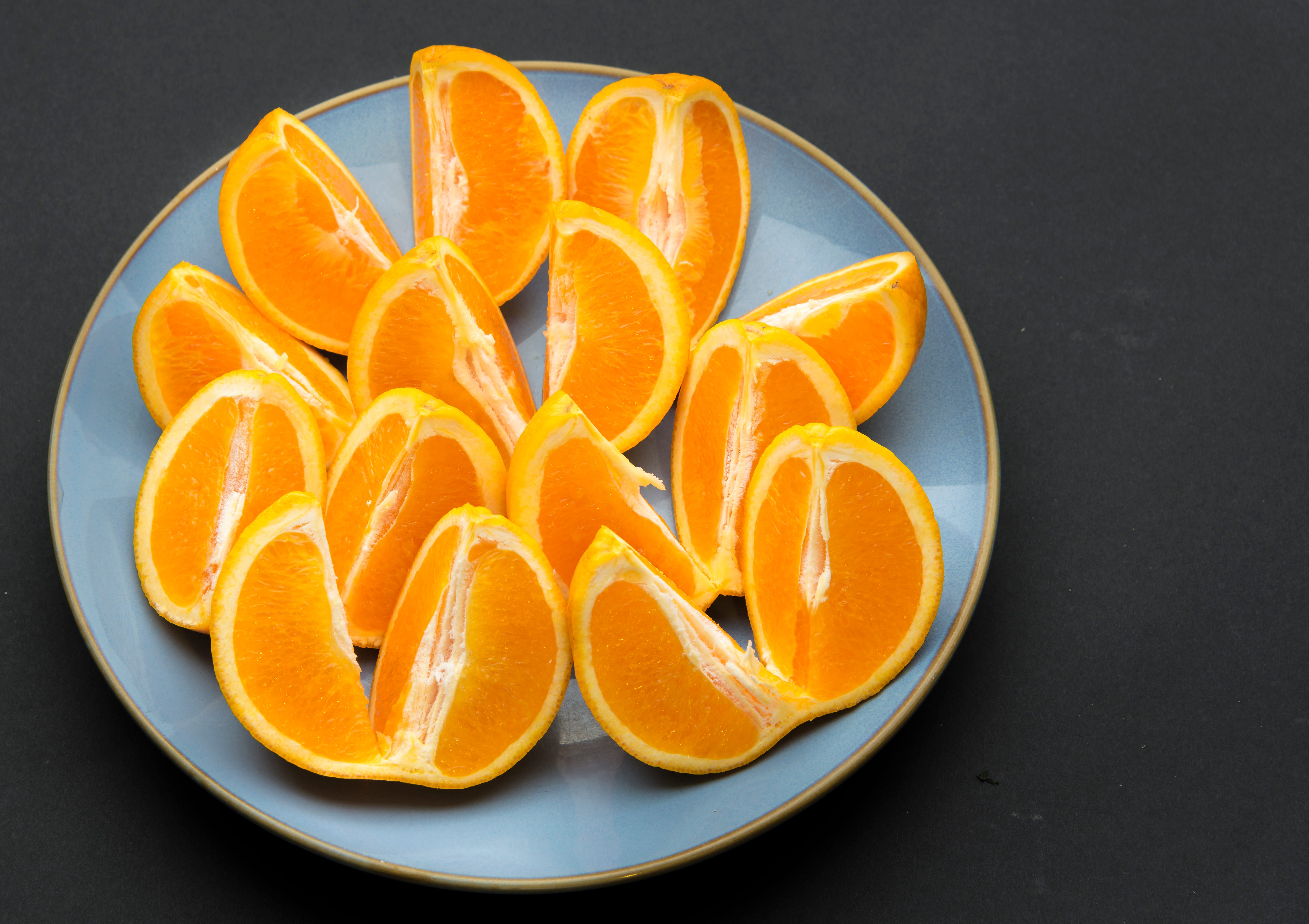 Quarter cut and unpeeled pieces of orange fruit arranged on...